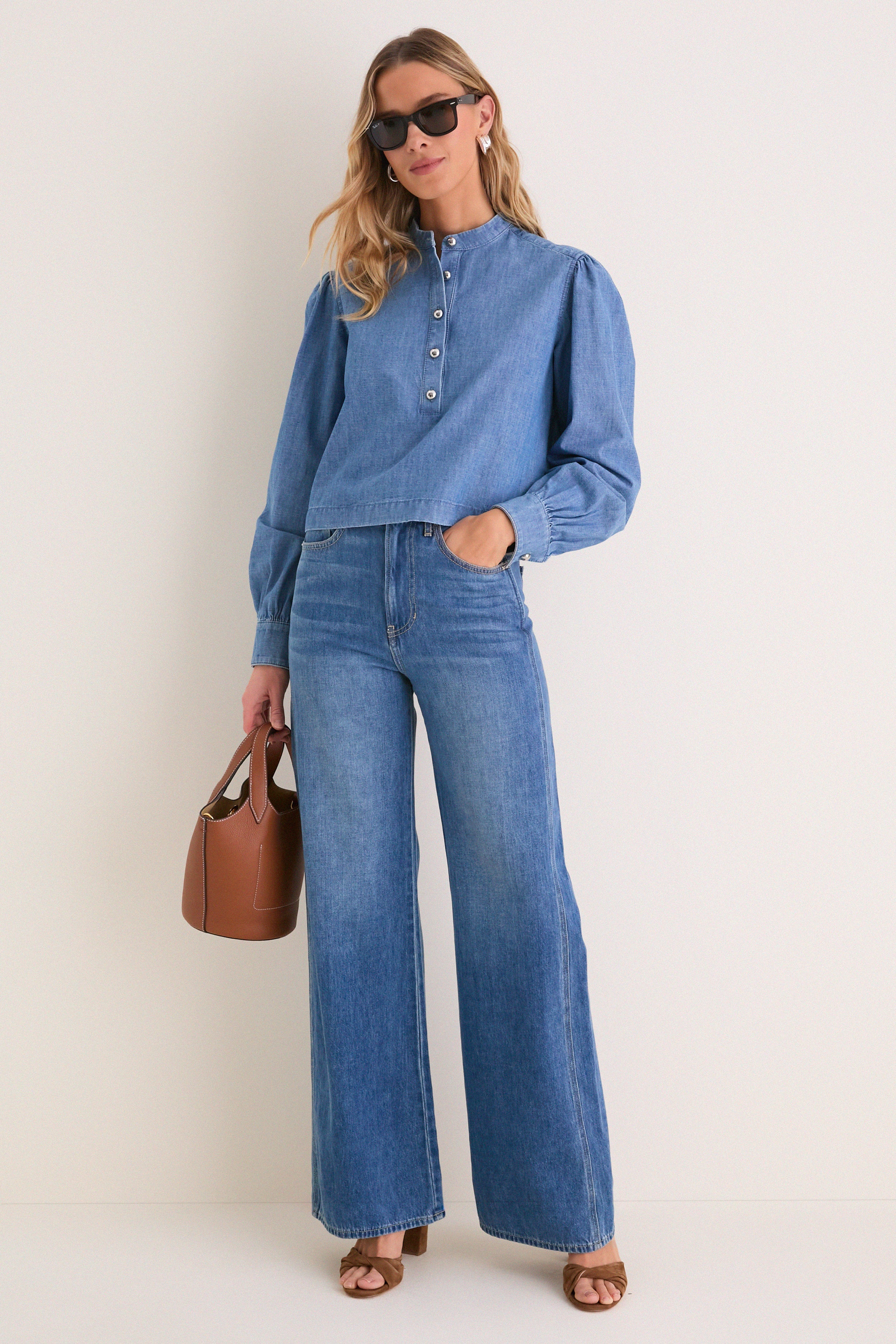 Model showcases the Indigo Denim Margot Top, a classic, effortlessly stylish blouse with a mandarin collar and button placket, paired with matching jeans and chic accessories.