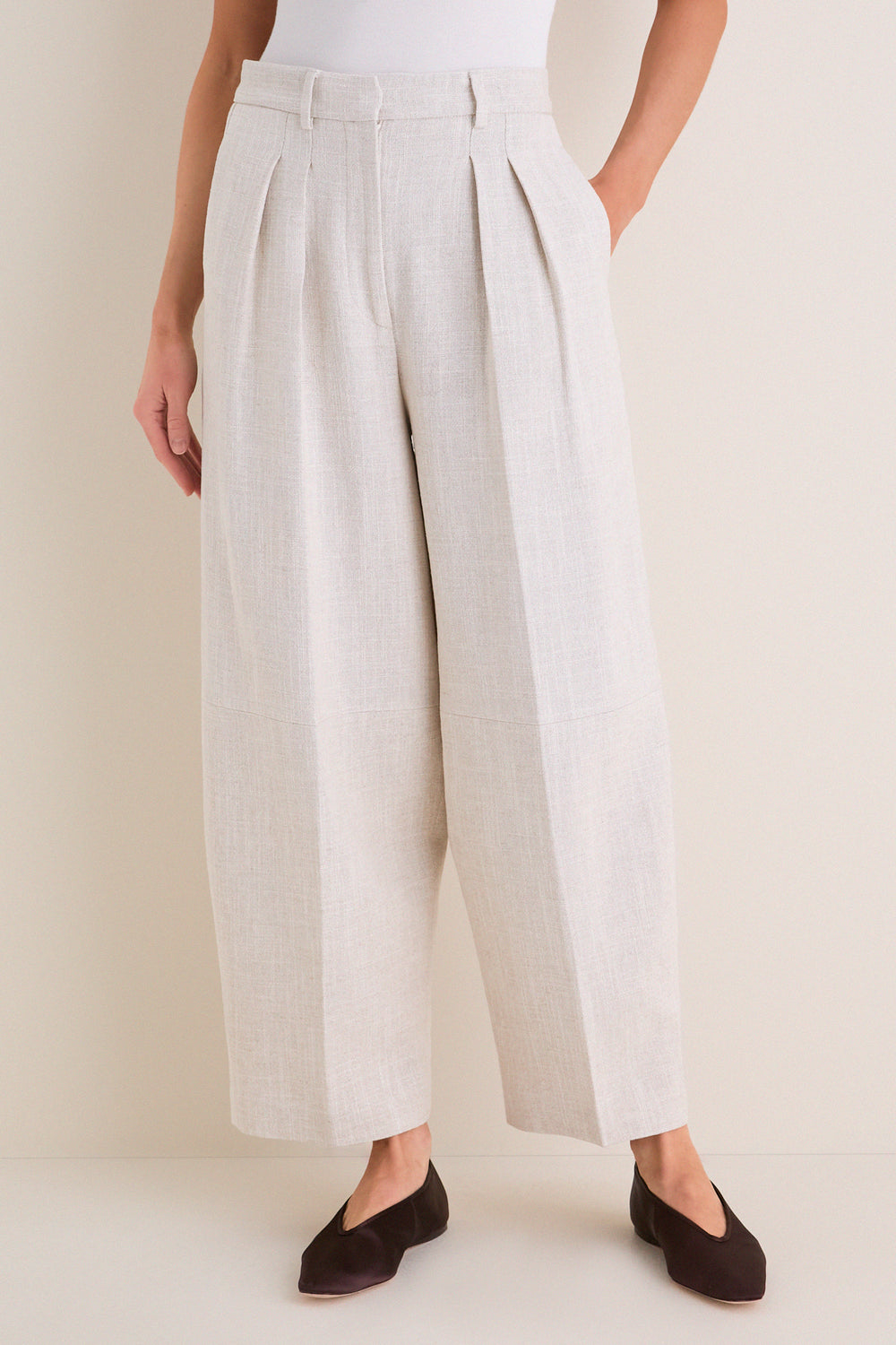 Model wearing Mortar Melange Dash Pants, classic wide-leg culottes with pleats and cropped barrel-leg design, paired with flats for an effortless, high-end look.