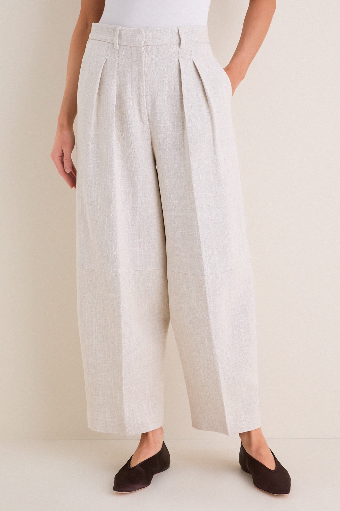 Model wearing Mortar Melange Dash Pants, classic wide-leg culottes with pleats and cropped barrel-leg design, paired with flats for an effortless, high-end look.