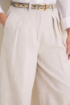Close-up of the classic Mortar Melange Dash Pants in light-beige linen, featuring pleats and a chic snakeskin belt, offering an effortless, high-end look.