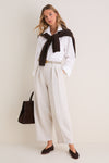 Model wearing the classic Mortar Melange Dash Pants with pleated barrel-leg silhouette, paired with a white shirt and brown flats for an effortless, high-end look.