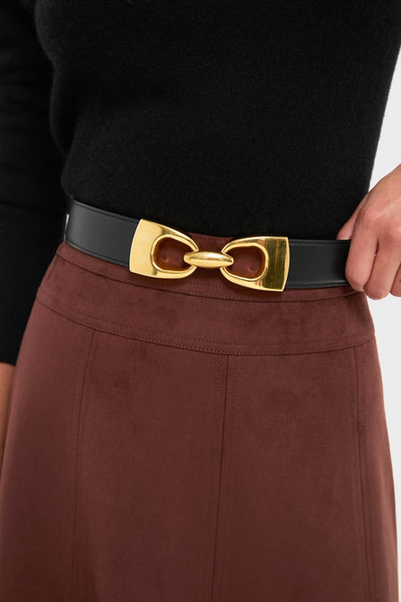 Close-up of a waist wearing a classic Black Horsebit Belt with an oversized gold-tone buckle, paired with an effortless, high-end brown A-line skirt.