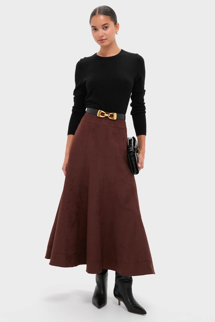 Model wearing a classic black long-sleeve sweater and dark brown maxi skirt, accentuated by an effortless, high-end Black Horsebit Belt with a gold-tone buckle.