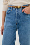 Person wearing a classic light-beige top with high-rise denim jeans, styled with the Saddle Hip to Waist Skinny Belt, featuring elegant gold hardware for an effortless, high-end look.