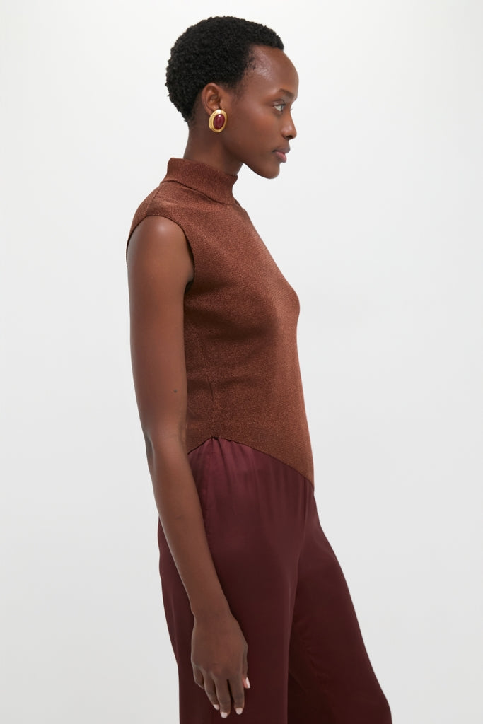 Model wearing the Rust Edith Top, a classic, sleeveless high-neck piece, paired with burgundy trousers, showcasing an effortless and high-end style with fun, rich textures.