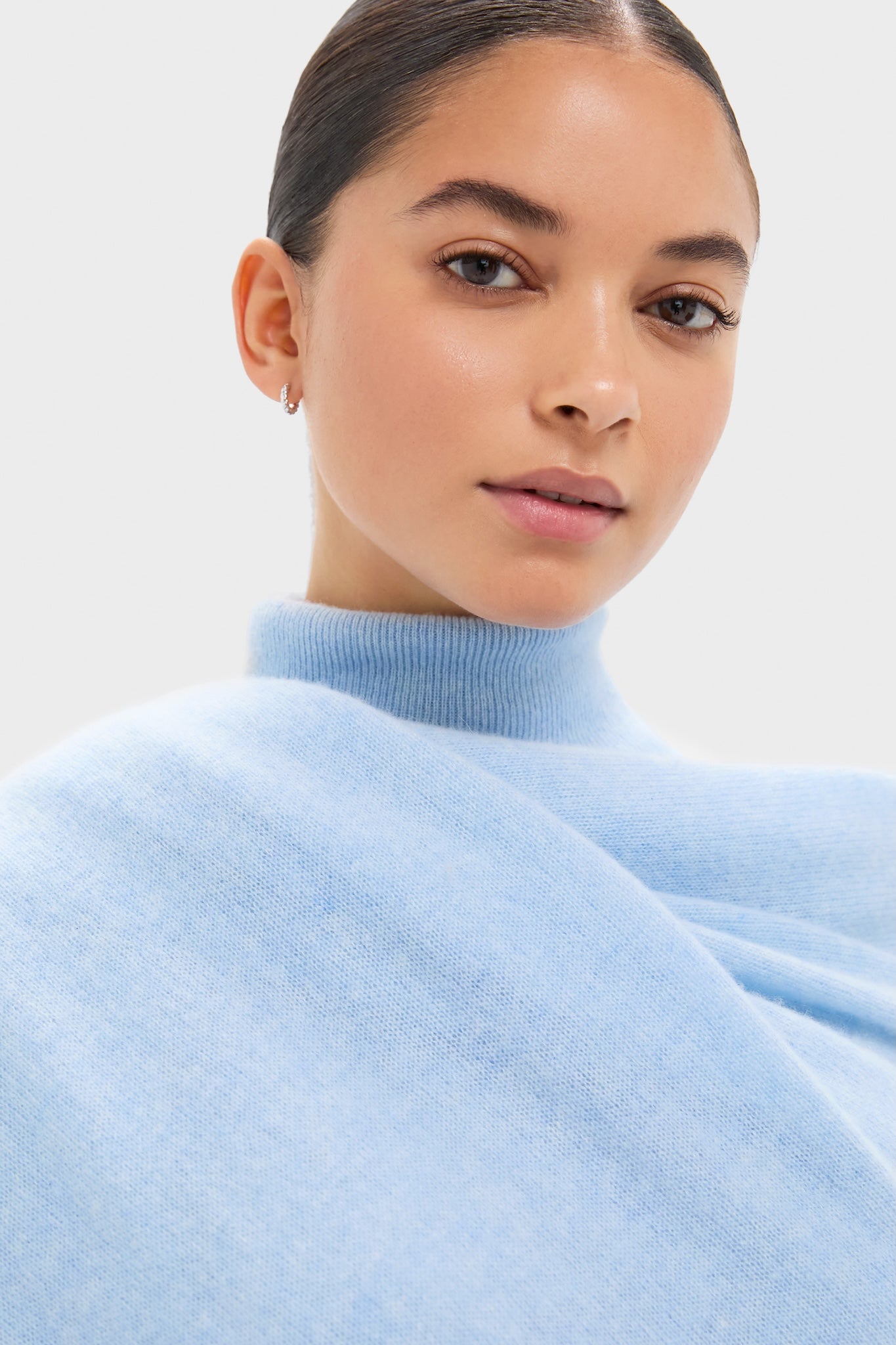 Young person in light-blue turtleneck showcases an Ice Blue Cashmere Blanket Scarf, epitomizing effortless, high-end style with its classic, luxurious cashmere softness.