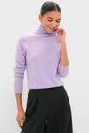 Woman wearing the Lavender Frost Cashmere Turtleneck Sweater with high-waisted black trousers, embodying an effortless, classic, and high-end style with a touch of fun.
