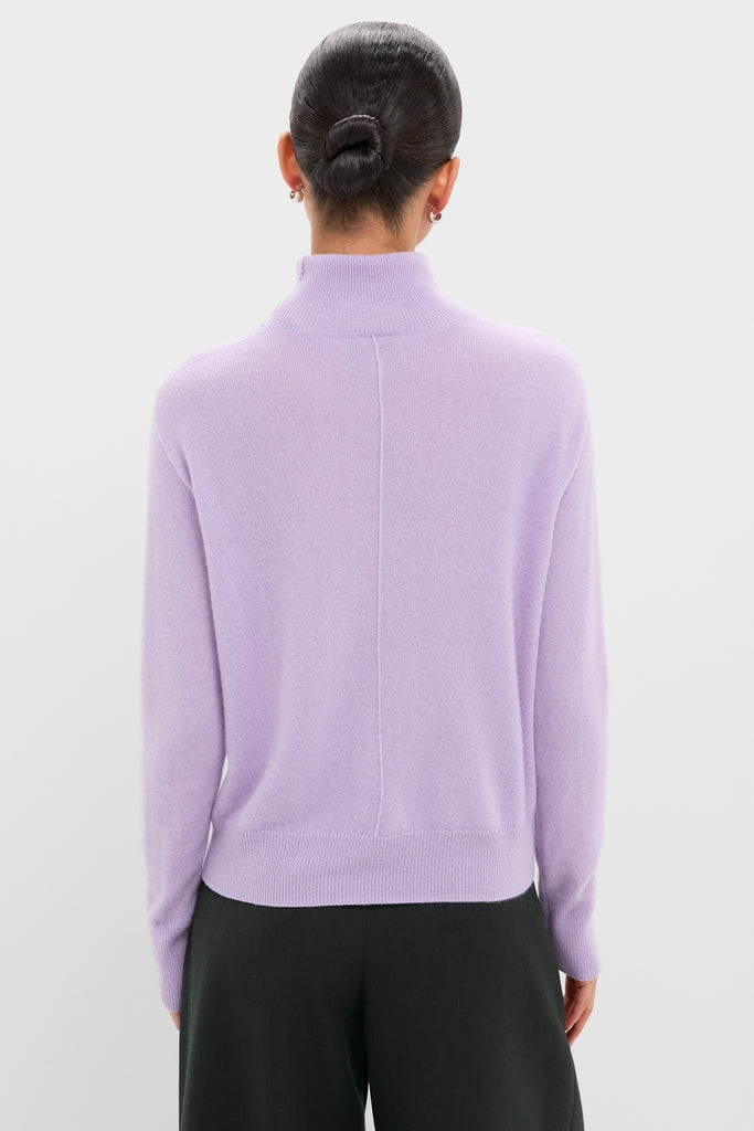 Woman in a classic Lavender Frost Cashmere Turtleneck Sweater, showcasing its effortless elegance, paired with loose-fit black trousers for a high-end, fun look.