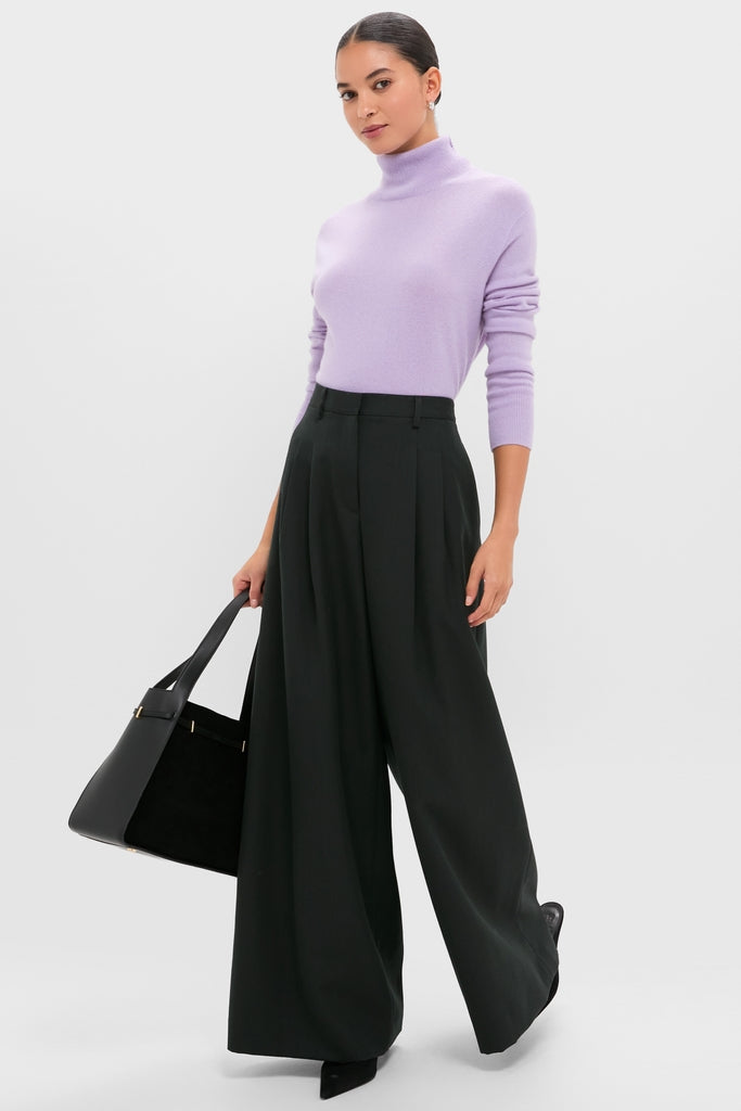 Woman in a classic, high-end Lavender Frost Cashmere Turtleneck Sweater paired with effortless wide-leg trousers, exuding fun and confidence, holding a structured tote bag.
