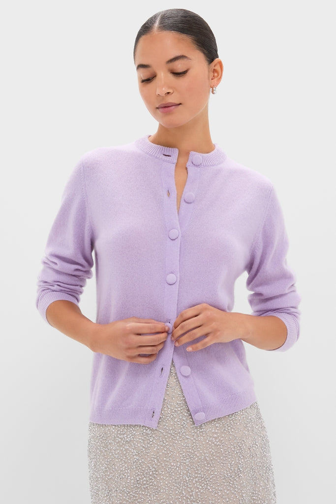 Model wearing the Lavender Frost Cashmere Quinn Cardigan, a classic, high-end piece with large buttons, effortlessly styled over a sequined skirt, embodying fun elegance.