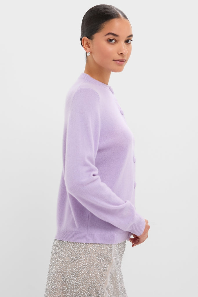 Young woman in profile wearing a classic Lavender Frost Cashmere Quinn Cardigan, exuding an effortless, high-end style with fun, sparkly skirt and elegant accessories.