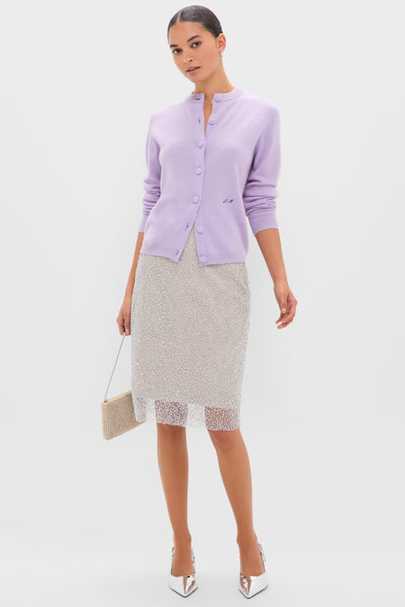 Model in a classic Lavender Frost Cashmere Quinn Cardigan, paired with an effortless silver sequin skirt and fun rhinestone clutch, exuding high-end style with metallic heels.