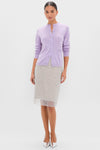 Woman wearing the Lavender Frost Cashmere Quinn Cardigan, a classic, soft lavender button-up with round neckline, paired with a semi-sheer dotted skirt and metallic heels. Effortless, high-end style.