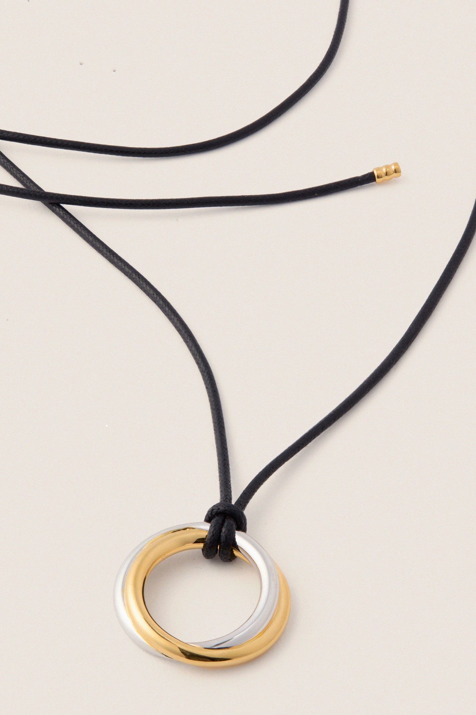 Mixed Lucy Williams Entwine Pendant Cord Necklace features interlocking gold and silver rings on an adjustable black cord, offering a classic, effortless, and high-end touch to any outfit.