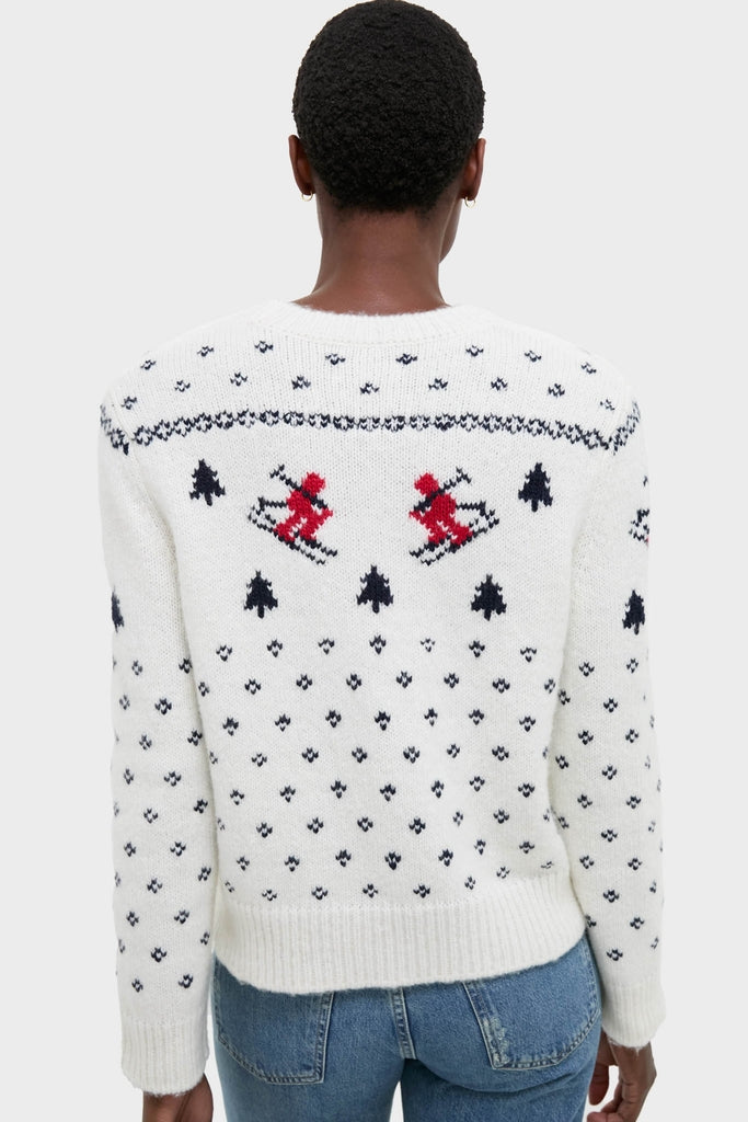 Person wearing Ski Lodge Crew Sweater with classic alpine motifs, featuring navy geometric patterns and intarsia knit skiers, styled effortlessly with jeans for a high-end, fun look.