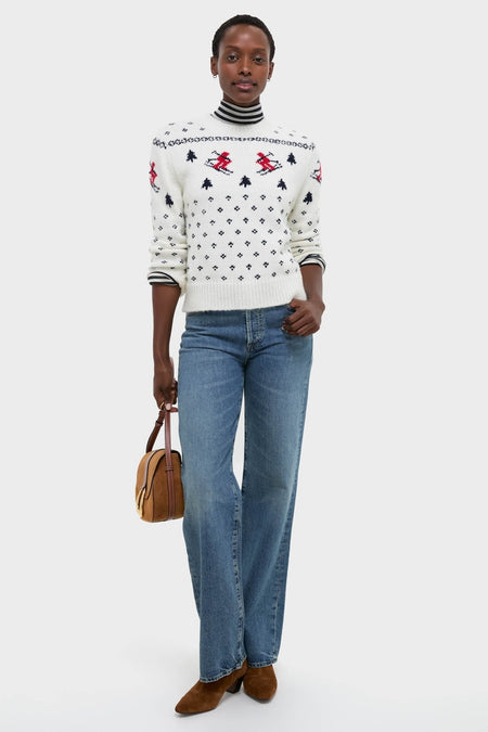 Woman models Ski Lodge Crew Sweater with classic Nordic motifs, layered over striped turtleneck, paired with jeans and suede boots, exuding effortless, high-end, fun style.