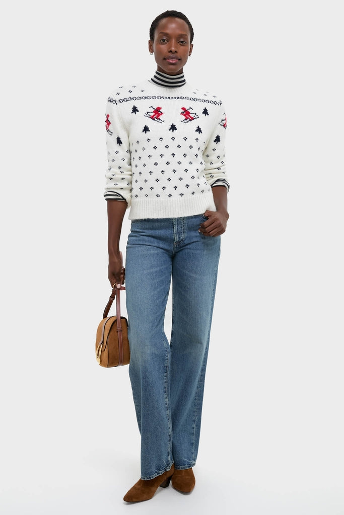 Woman models Ski Lodge Crew Sweater with classic Nordic motifs, layered over striped turtleneck, paired with jeans and suede boots, exuding effortless, high-end, fun style.