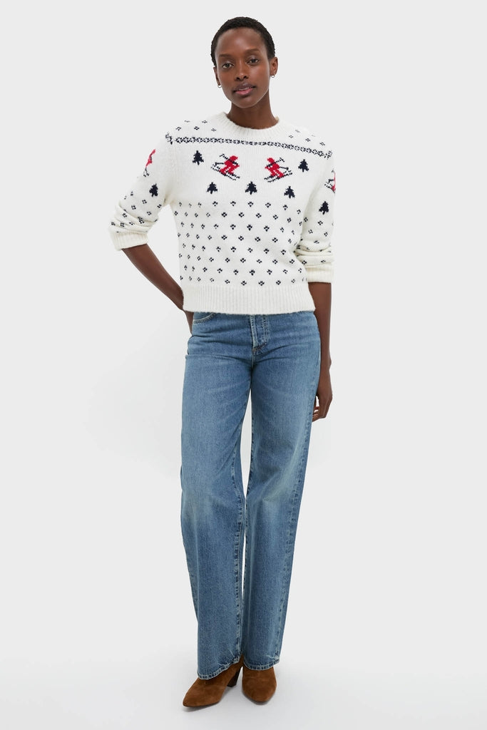 Model in Ski Lodge Crew Sweater, showcasing classic alpine motifs, paired effortlessly with denim jeans and brown suede boots for a high-end, fun, winter-ready look.