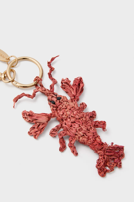 Lobster Raffia Bag Charm: A classic, fun, and effortless lobster-shaped charm made of braided raffia with black bead eyes, attached to a high-end gold-tone key ring.