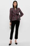 Woman models the classic Tartan Tie Front Bow Bea Blouse, featuring an effortless wrap style and peplum waist, paired with sleek black velvet pants and a chic clutch.