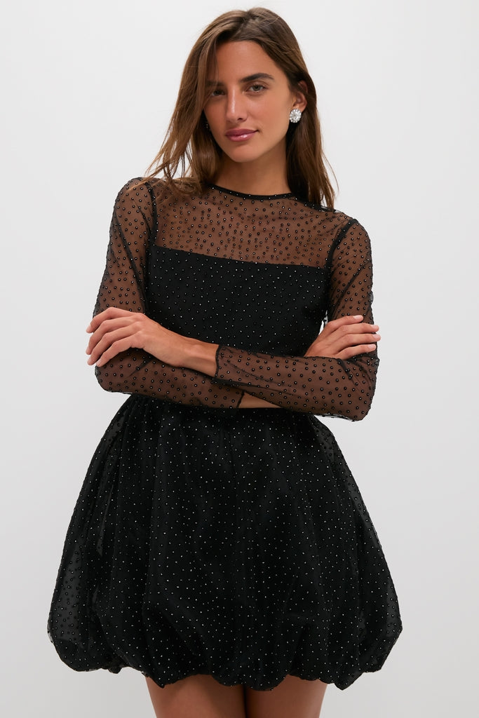 Model in Black Saoirse Mini Dress featuring sheer dotted mesh sleeves and bubble hem, showcasing an effortless, high-end, and fun classic style for nighttime elegance.