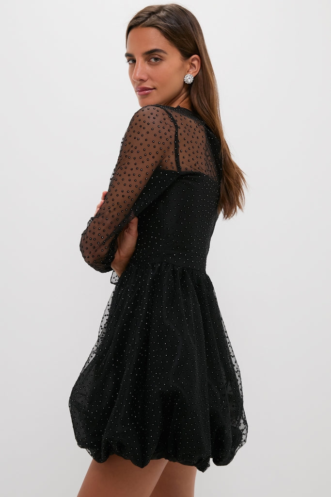 Young woman in a Black Saoirse Mini Dress with sheer dotted mesh, bubble hem, and elegant embellishments, exuding effortless, high-end style, perfect for a fun, classic night out.