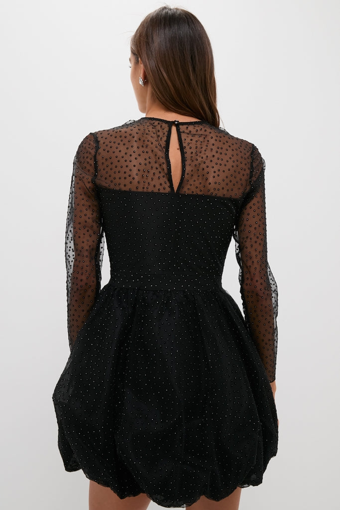 Black Saoirse Mini Dress with dotted mesh, sheer sleeves, and bubble hem, styled effortlessly for a modern, fun, and high-end look. Classic elegance reimagined.