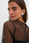Close-up of Black Saoirse Mini Dress with dotted mesh, sheer neckline, and bubble hem, paired with crystal-like stud earrings for an effortless, classic, and high-end look.