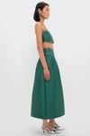 Model in profile wears the classic Evergreen Tashi Two Piece Maxi Dress, featuring an effortless emerald crop top and full skirt with scalloped rhinestone details, epitomizing a fun, high-end look.