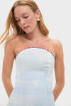 Young woman in a light-blue, strapless Nautical Print Ava Bustier Maxi Dress with classic pearl-style earrings, embodies effortless, high-end style against a plain backdrop.