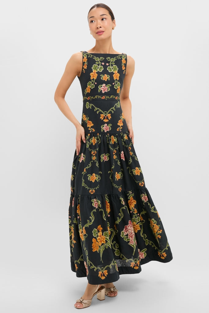 Model wearing the Cordillera Abeja Maxi Dress, a classic, effortless piece featuring a square neckline and tiered skirt with stylized floral motifs, embodying high-end, fun fashion.