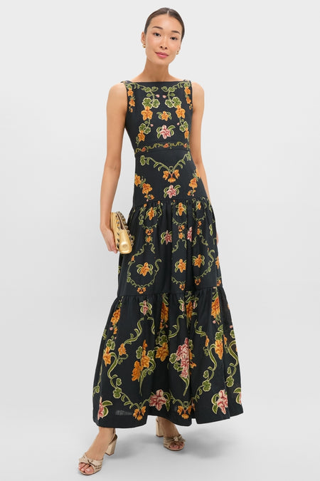 Woman in Cordillera Abeja Maxi Dress featuring a classic vine floral pattern, paired with a metallic-gold clutch and neutral sandals, embodying effortless, high-end style for any occasion.