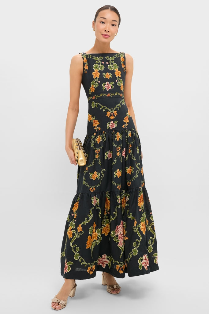 Woman in Cordillera Abeja Maxi Dress featuring a classic vine floral pattern, paired with a metallic-gold clutch and neutral sandals, embodying effortless, high-end style for any occasion.