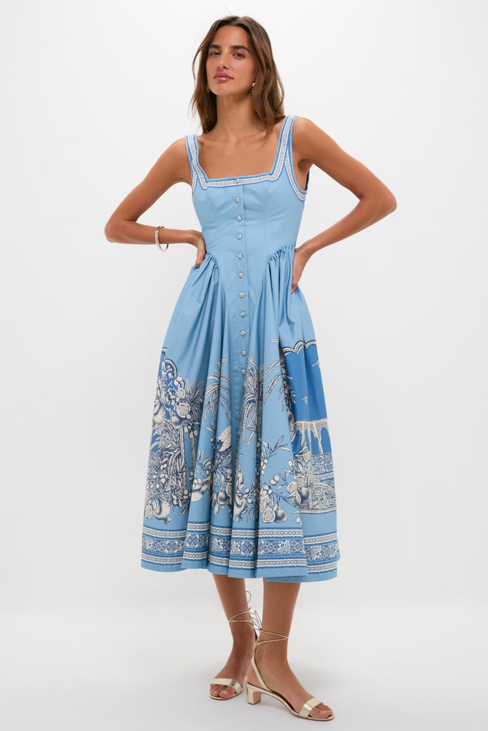 Model in the classic Blue Villa Romantica Midi Dress with a fitted bodice, toile print, and plunging back, embodying effortless, high-end style with fun gold sandals.