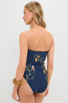 Woman wearing Laguna Durazno Embroidered One Piece, a classic, high-end strapless navy swimsuit with floral vines, accessorized with gold jewelry, epitomizing effortless elegance and fun.
