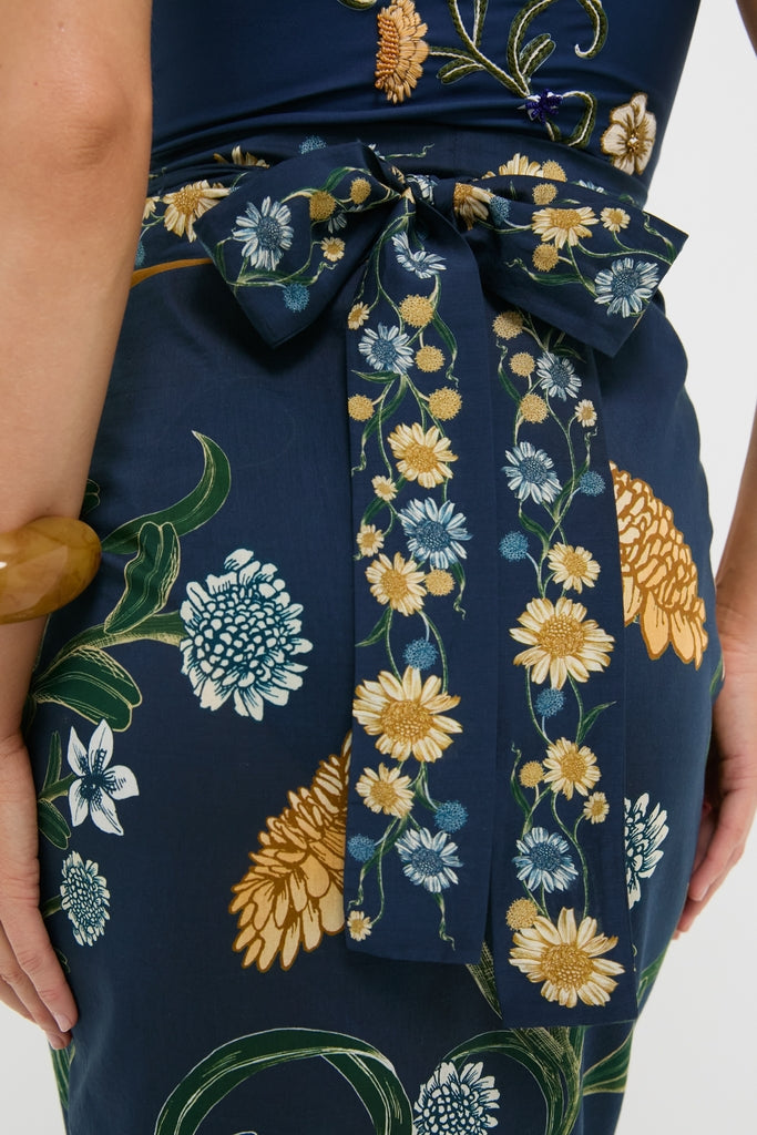Close-up of Laguna Lavanda Midi Sarong's back, showcasing a classic floral pattern with an effortless, high-end navy-blue fabric and a fun bow-tied sash at the waist.