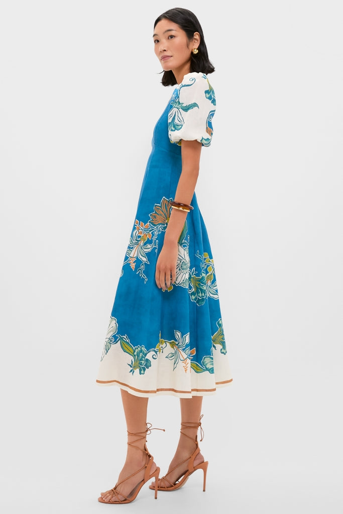 Blue Luda Midi Dress: A classic, high-end fashion piece with puff sleeves and floral print, paired effortlessly with tan sandals and gold accessories for a fun, stylish look.