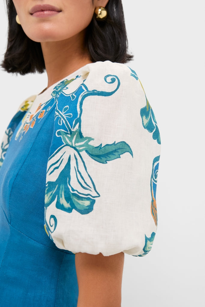 Blue Luda Midi Dress with a classic fitted blue bodice and fun puff sleeves featuring floral motifs, worn effortlessly by a woman showcasing its high-end design.