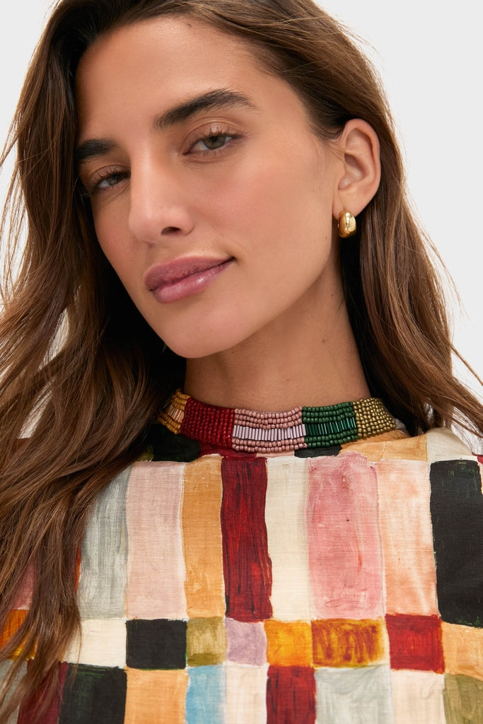 Young woman in Multi Marjorelle Mini Dress with classic beaded neckline and gold hoop earring, embodying an effortless, high-end style.