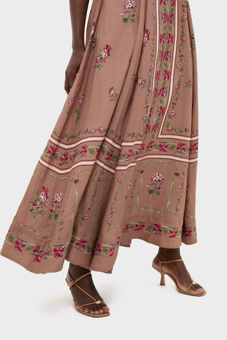 Quebrada Jaspe Maxi Dress in floral print with decorative border, showcasing an effortless, classic A-line silhouette paired with tan strappy sandals for a high-end, fun look.