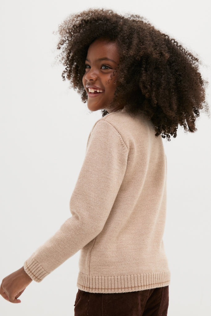 Young girl in a classic, high-end Jacquard Head Horse Jumper, showcasing an embroidered horse motif and stripes, smiling effortlessly and having fun.