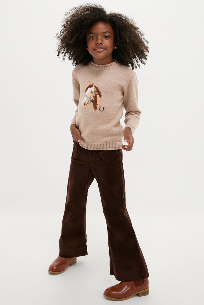 Young girl in a classic Jacquard Head Horse Jumper, effortlessly styled with wide-leg corduroy pants and ankle boots, exuding fun and high-end charm.