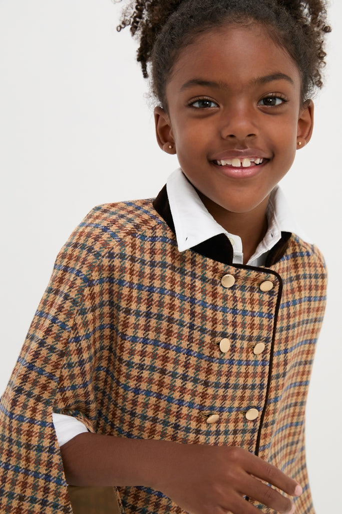 Young girl wearing classic Checked Double Breasted Cape in Brown with gold buttons and a velvet collar, embodying effortless, high-end style for fun, confident autumn layering.
