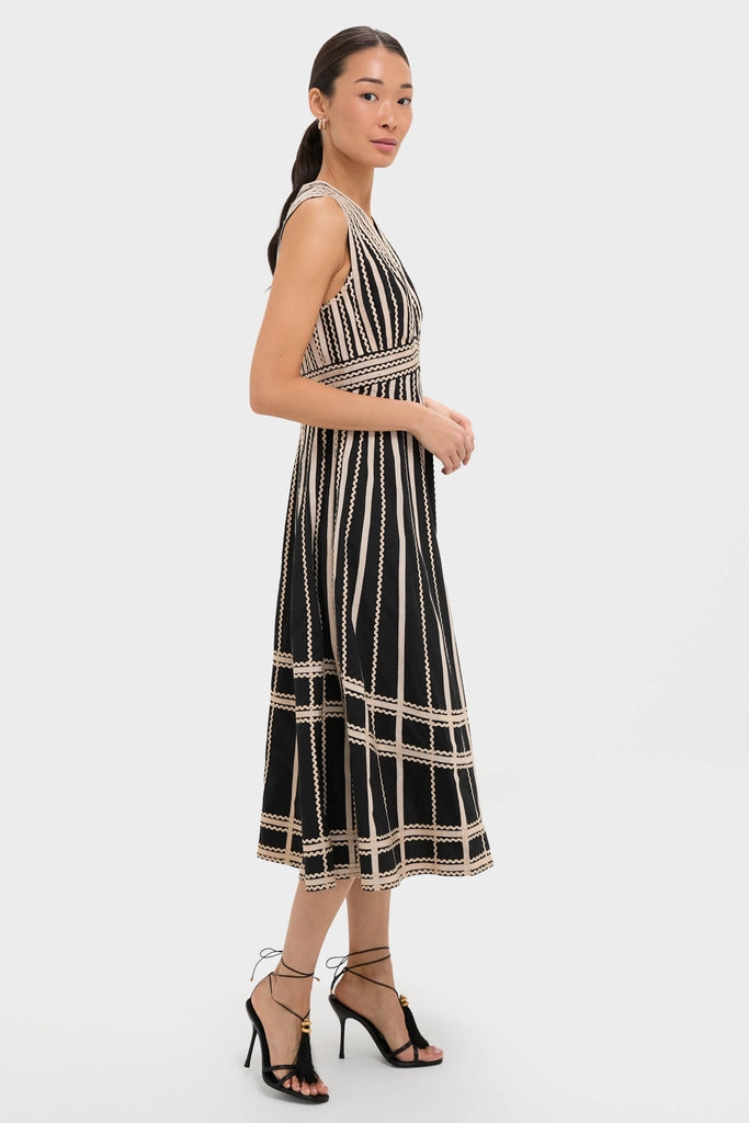 Woman in profile wearing the classic Noir Palermo Dress with a plunging neckline and A-line silhouette. Paired with high-end tassel-accented sandals for an effortless, fun look.