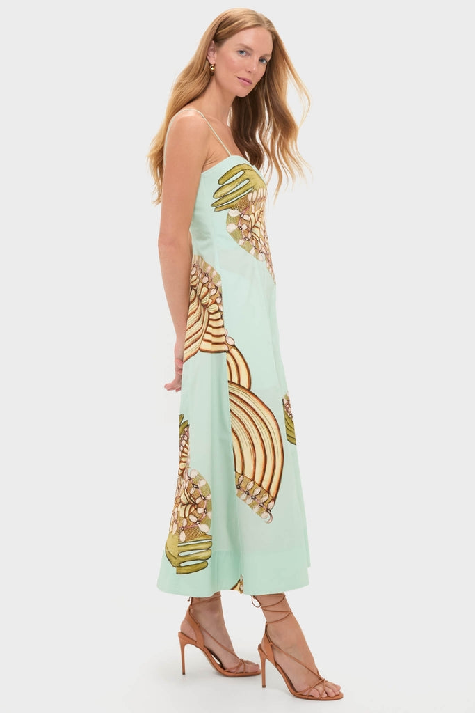 Woman in classic Water Blossoms Vesela Dress, featuring an effortlessly chic mint-green, seashell-patterned design, paired with fun, high-end tan leather stiletto sandals.