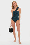 Eclipse Flora Capri Maillot: A classic, high-end swimsuit with a floral print and ruffled single strap, styled with a fun woven handbag for an effortless look.