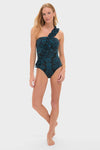 Woman wearing the Eclipse Flora Capri Maillot, a classic one-shoulder swimsuit with a teal floral pattern and ruffle detail, embodying effortless style and high-end elegance.