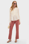 Model in classic Garden Rose Agatha Jean, featuring an effortless ivory blouse with pintuck detail, rust straight-leg pants, and fun strappy sandals, embodying high-end style.