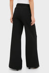 Back view of person wearing Black Pillar Wide Leg Pant; high-waisted, wide-leg, with back welt pockets and slits, embodying classic, effortless, and high-end style.