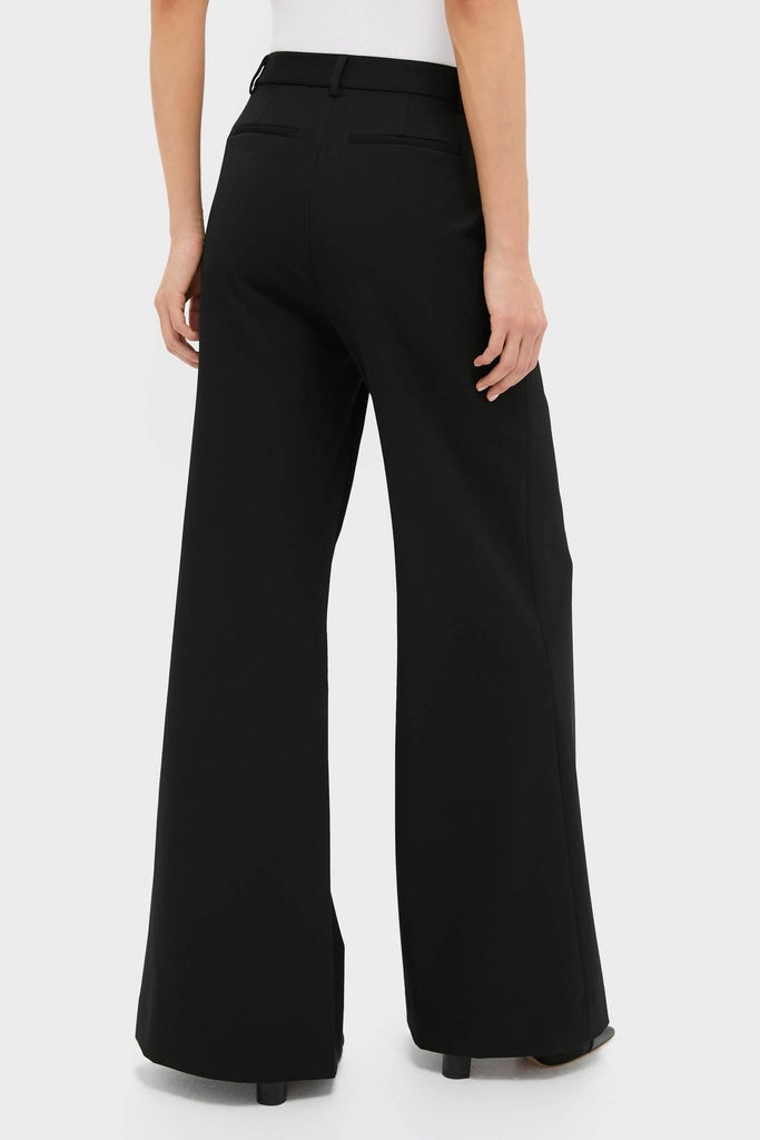 Back view of person wearing Black Pillar Wide Leg Pant; high-waisted, wide-leg, with back welt pockets and slits, embodying classic, effortless, and high-end style.